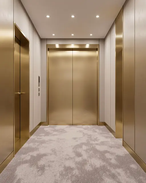A clean empty elevator lobby with polished brass doors, patterned soft carpet, and recessed ceiling lighting
