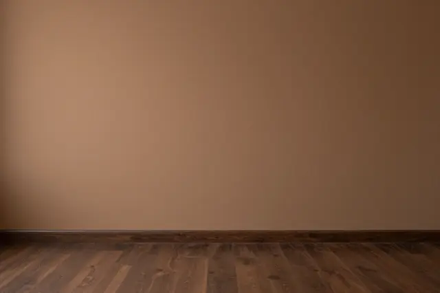 Empty interior with warm brown wall, dark wooden floor and soft even lighting