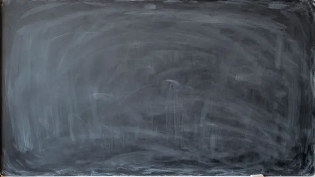 A clean empty dark chalkboard covered in soft, faint chalk smudge marks left from erasing.