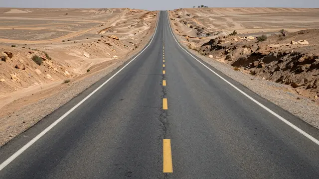 A long empty paved highway extends straight into the distance across arid desert terrain