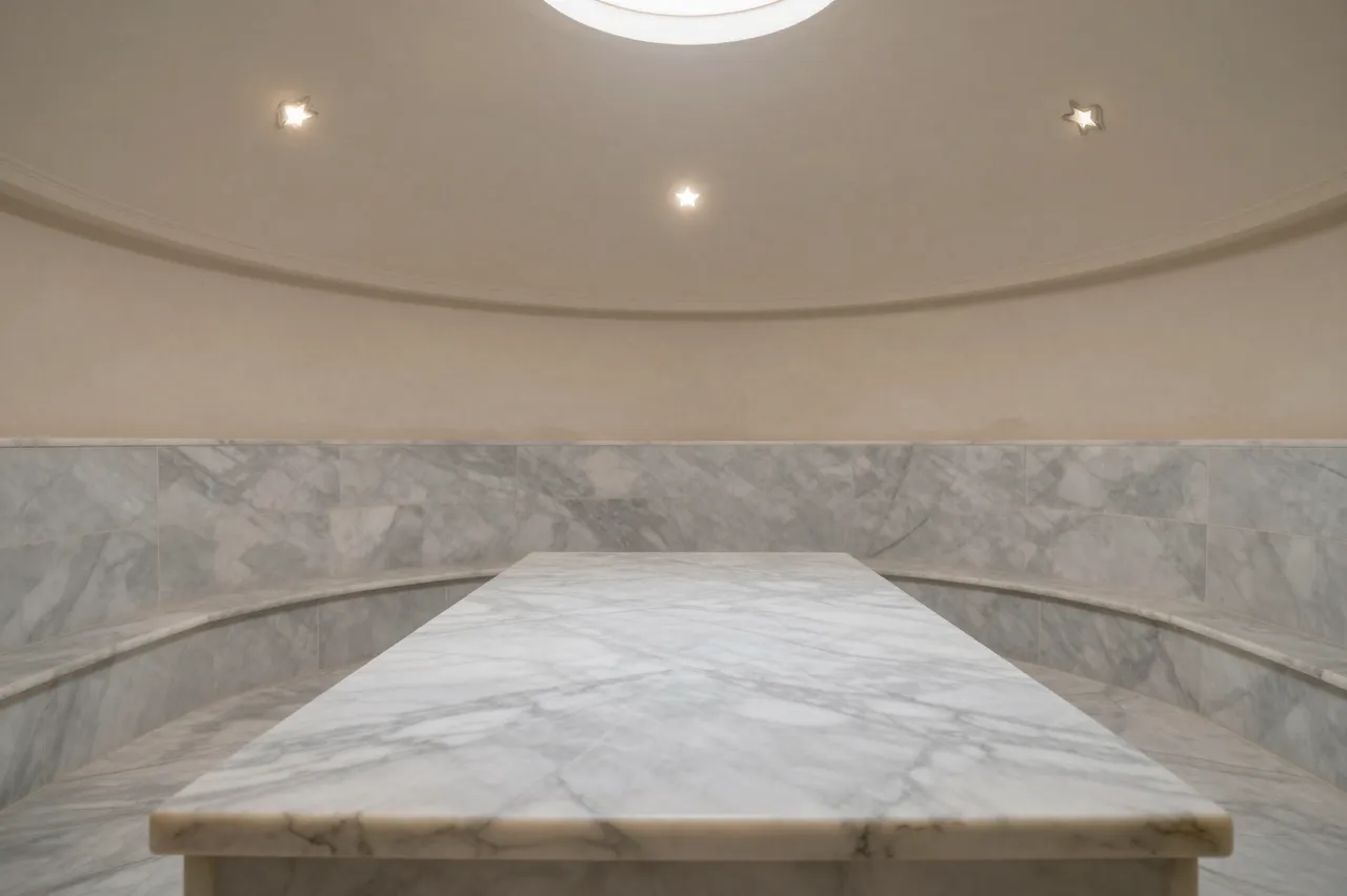 Unoccupied hammam steam room with a marble slab, domed ceiling, and small star skylights in soft haze.