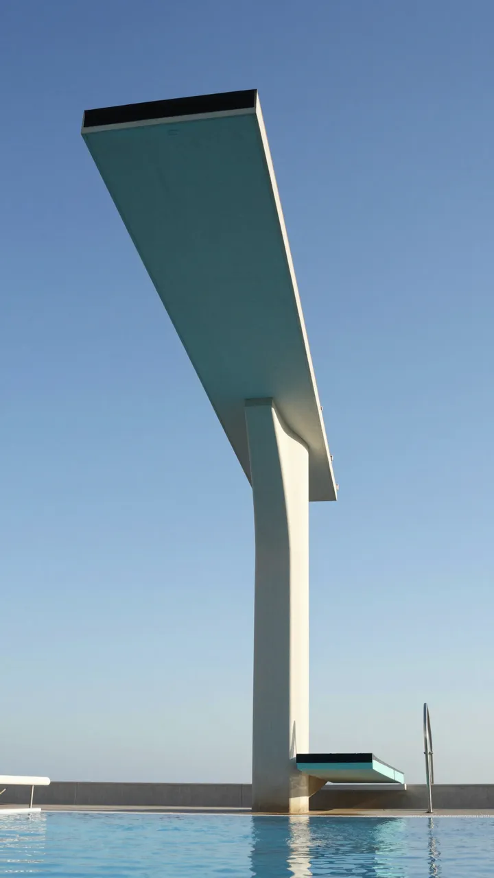 Low angle view of empty diving boards over an outdoor pool under a clear blue sky