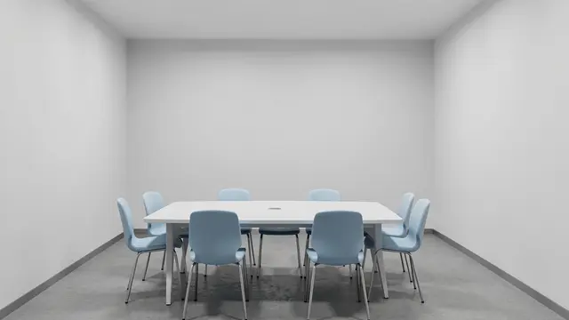 Empty conference room with a white table and pale blue chairs against blank light gray walls