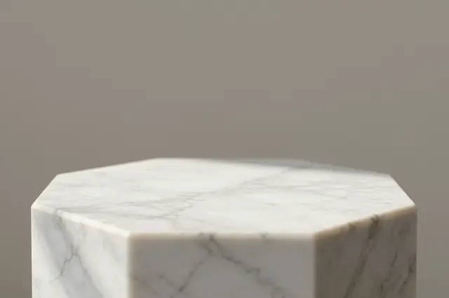 Close-up of an empty octagonal white marble podium against a neutral taupe background