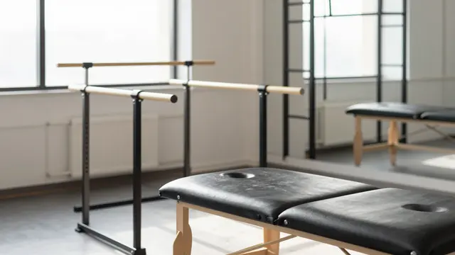 Unoccupied physiotherapy clinic interior with parallel bars, treatment tables and soft morning window light.