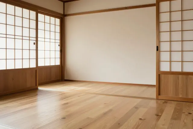 An empty room with wooden flooring, shoji sliding paper doors and plain bare walls.