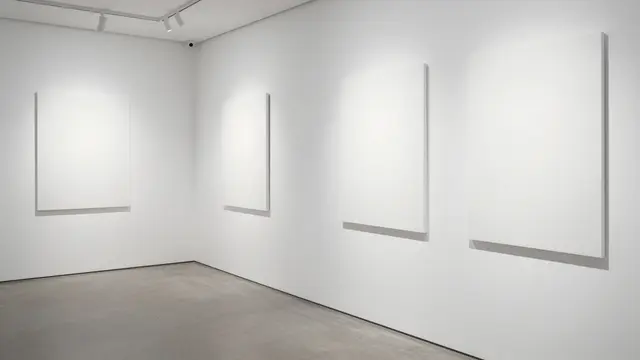 Minimalist empty white gallery space with blank canvases lit by overhead track lighting
