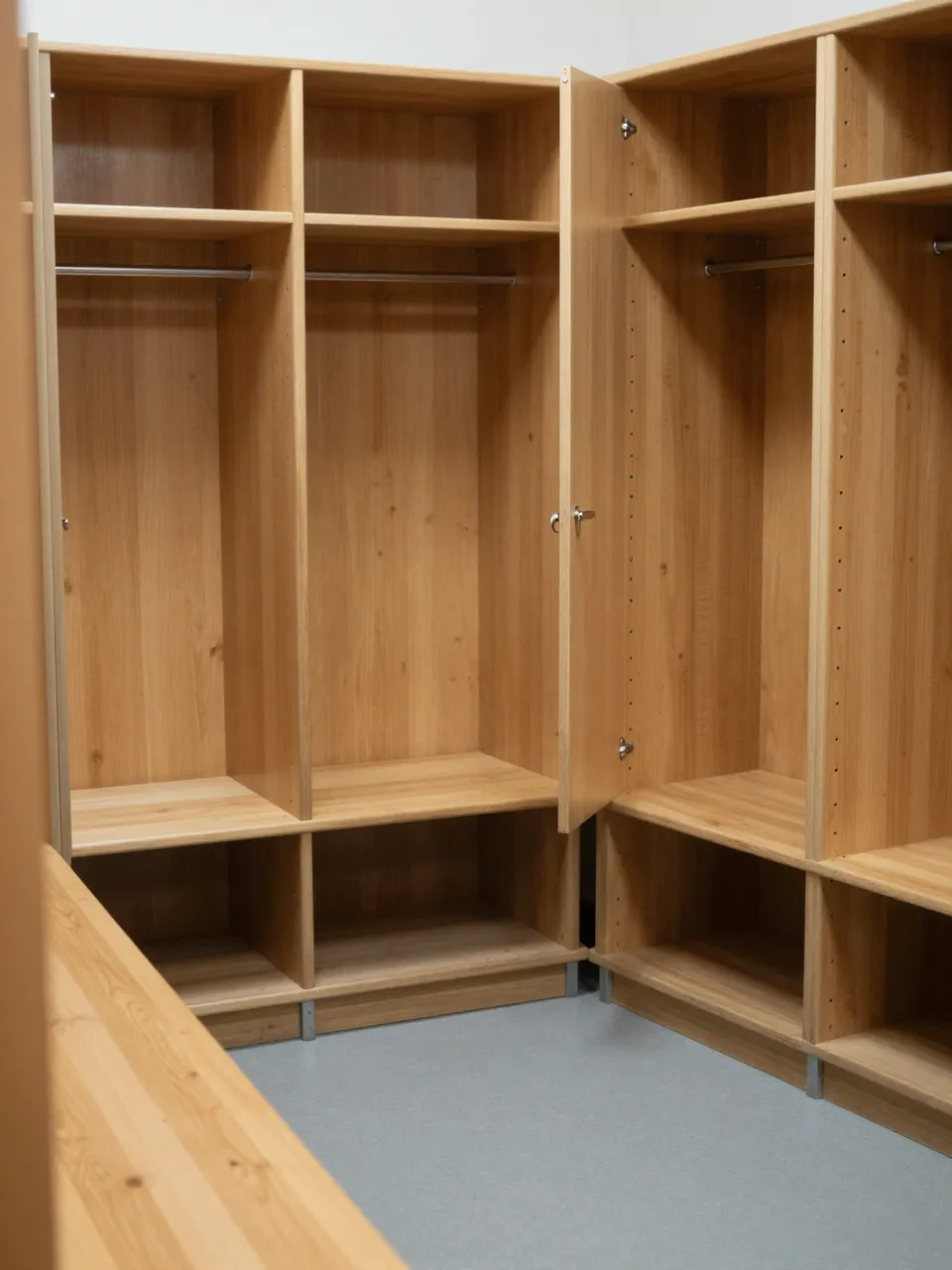 Unoccupied wooden lockers with open cubbies line the corner of a soft lit locker room.