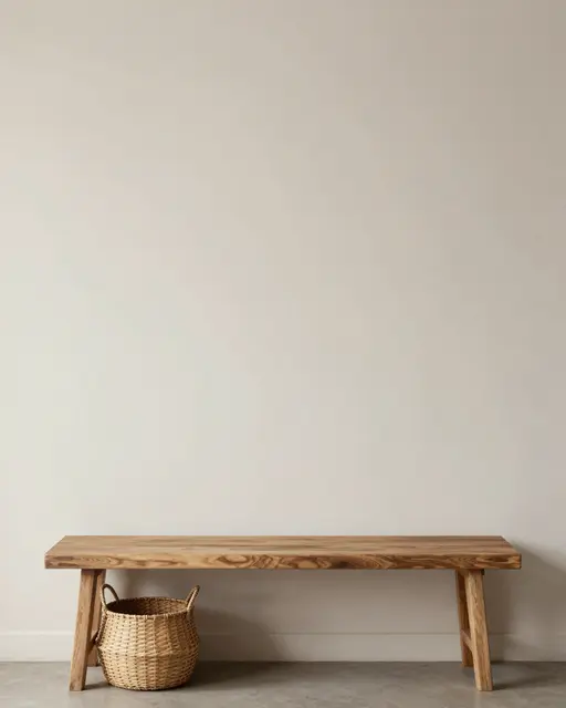 A wooden bench and woven basket sit against an empty light neutral wall with ample copy space