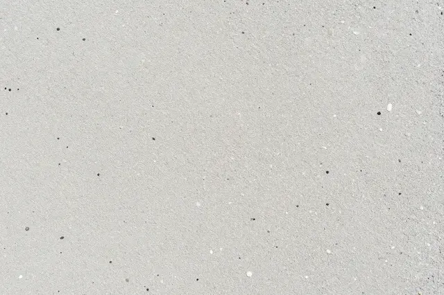 Top-down close-up of smooth light gray exposed aggregate concrete dotted with small pebbles