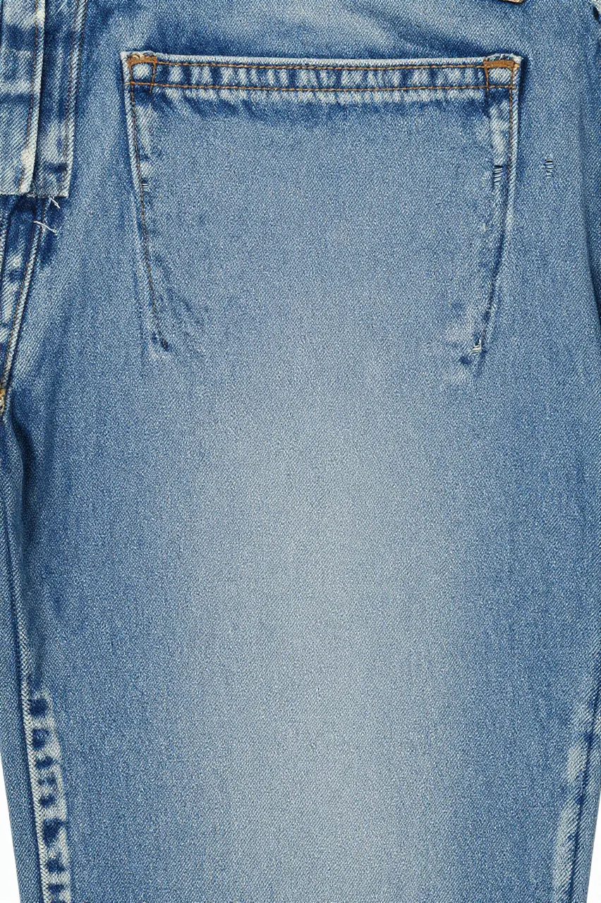 Close-up of light-wash faded denim fabric showing stitched pocket and soft whiskering details