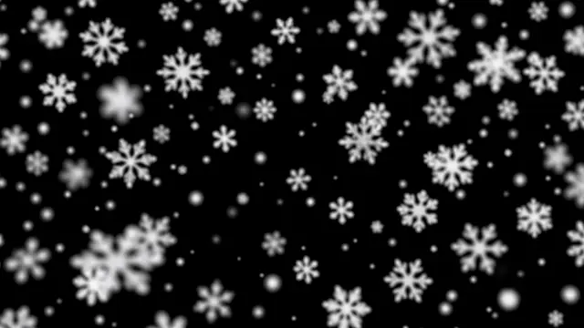 Out of focus soft white snowflakes drift gently across a solid pure black background