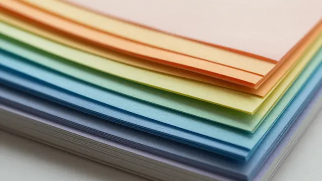 Close-up of a fanned stack of colored paper sheets arranged in soft rainbow order