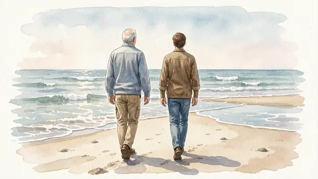 Seen from behind, an older senior man and adult son walk side by side along a sandy low-tide beach toward gentle ocean waves.