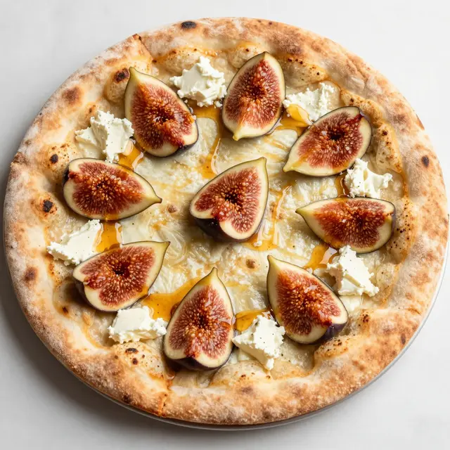Top view of a freshly baked flatbread pizza topped with figs, goat cheese, and honey drizzle on a light countertop.
