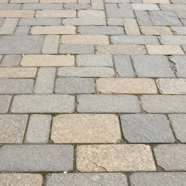 Top view of mixed gray and tan irregular flagstone paving with moss growing in the joints
