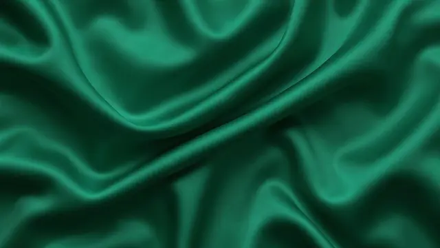 Smooth folded emerald green silk with soft flowing folds and glossy light reflections