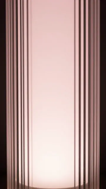Full frame close-up of vertical fluted glass with soft pale pink backlighting