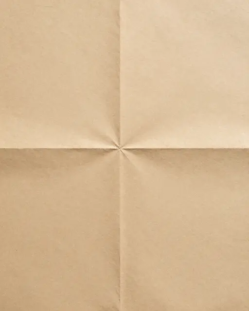 Full frame close-up of old tan folded paper with intersecting creases filling the entire frame