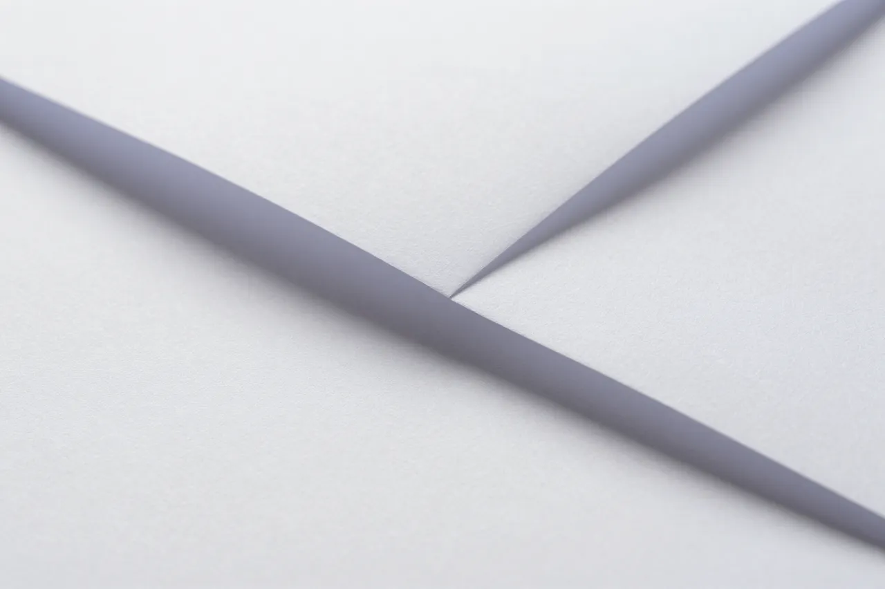 Close-up of folded white paper with sharp angled creases and soft shadowed edges