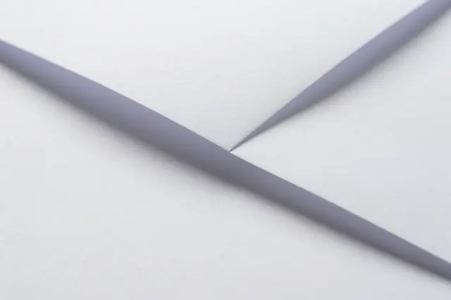 Close-up of folded white paper with sharp angled creases and soft shadowed edges