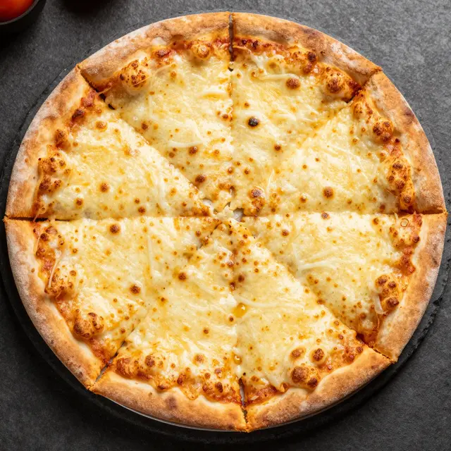 Top down view of a sliced baked cheese pizza resting on a dark stone platter