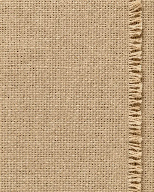 Close-up view of natural woven burlap fabric with a frayed fringed edge along the right side