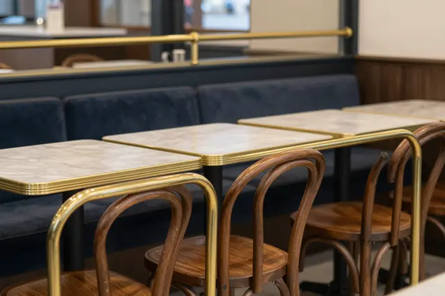 Empty French bistro interior with bentwood chairs, marble tables, brass rails and upholstered booths