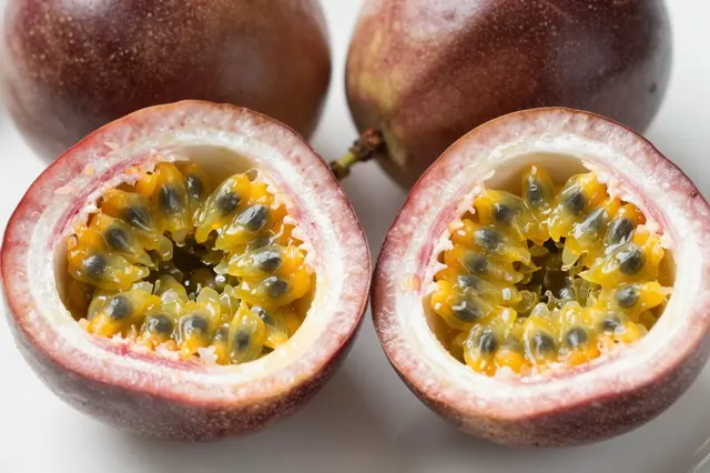 Close-up of halved passion fruit showing juicy pulp and seeds alongside whole fruits on a light surface