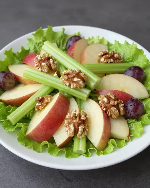 Prepared Waldorf salad arranged on a white plate over crisp lettuce with apples, celery, walnuts and grapes.