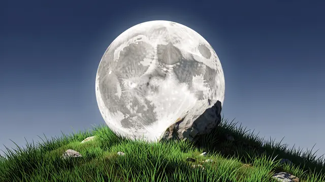 A large full moon rests like a boulder atop a grassy hill under a clear dark blue sky