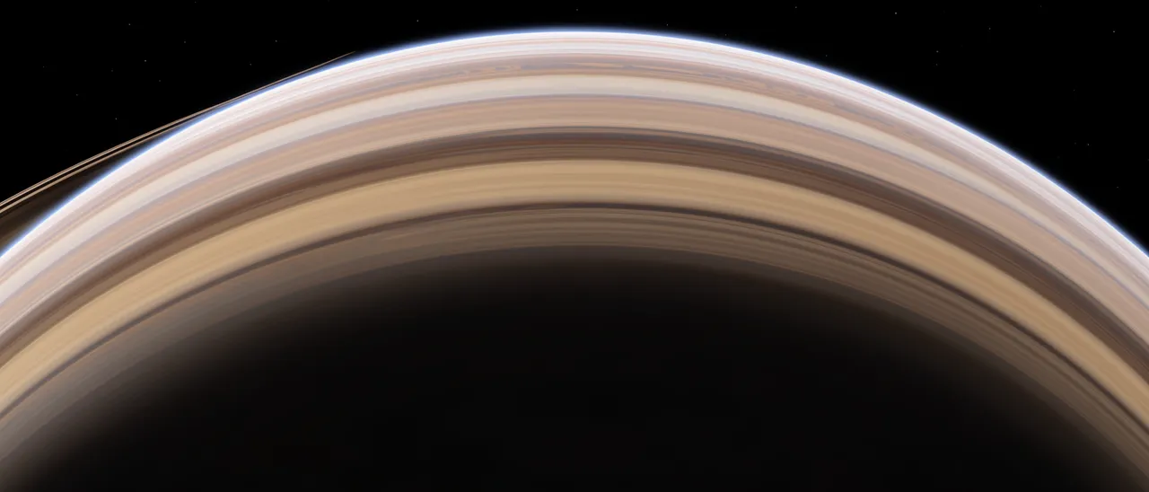 The upper curved edge of a banded ringed gas giant stretches across black starry space