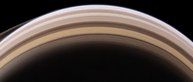 The upper curved edge of a banded ringed gas giant stretches across black starry space