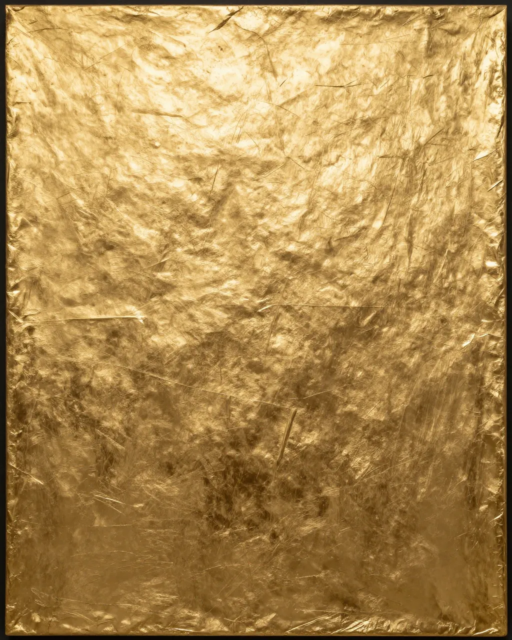 Full frame close-up of textured gold leaf gilding with crinkled seams and fine cracks under soft light