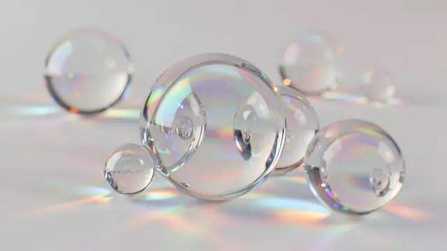 Transparent glass spheres cast iridescent rainbow refractions across a pale smooth surface.