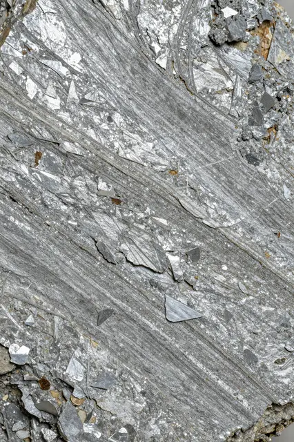 Full frame close-up of silvery flaky mica schist with parallel layered mineral structure