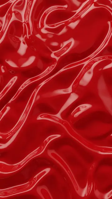 Vertical full frame view of smooth glossy cherry red liquid with flowing curved ripples and soft reflective highlights