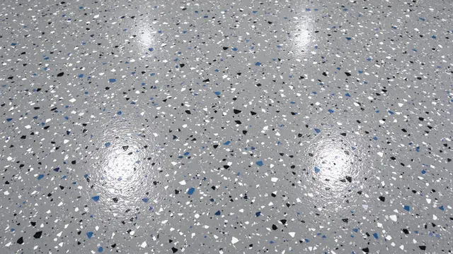 Top view of a glossy gray epoxy floor scattered with black, white, and blue decorative flakes filling the full frame