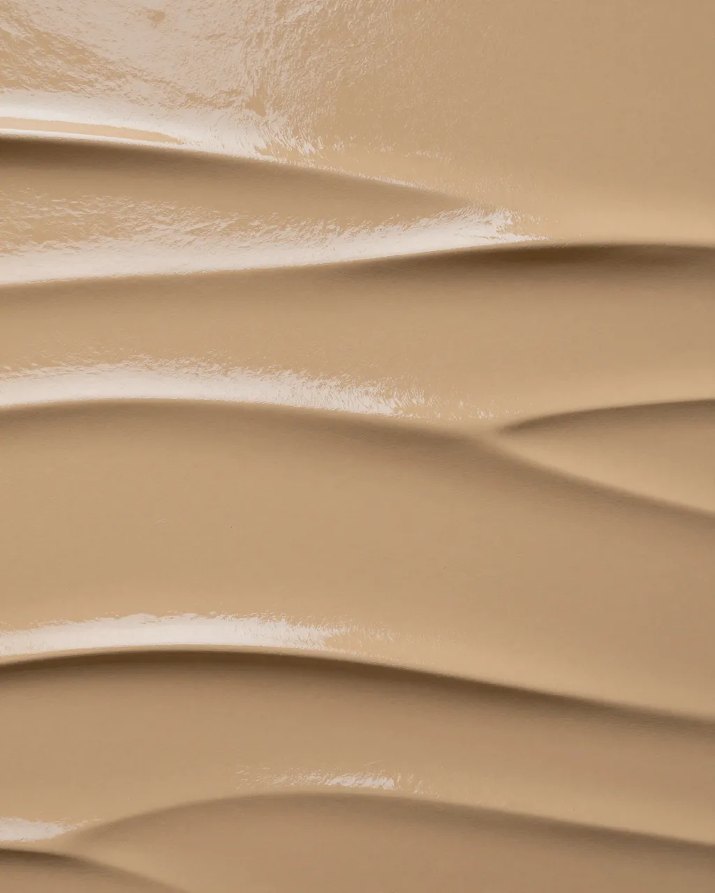 Full frame close up of glossy burnished ochre tadelakt plaster with soft wavy ridges under flat light