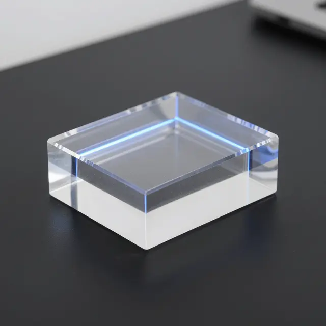 A clear acrylic block with an embedded glowing blue line rests on a matte black desk