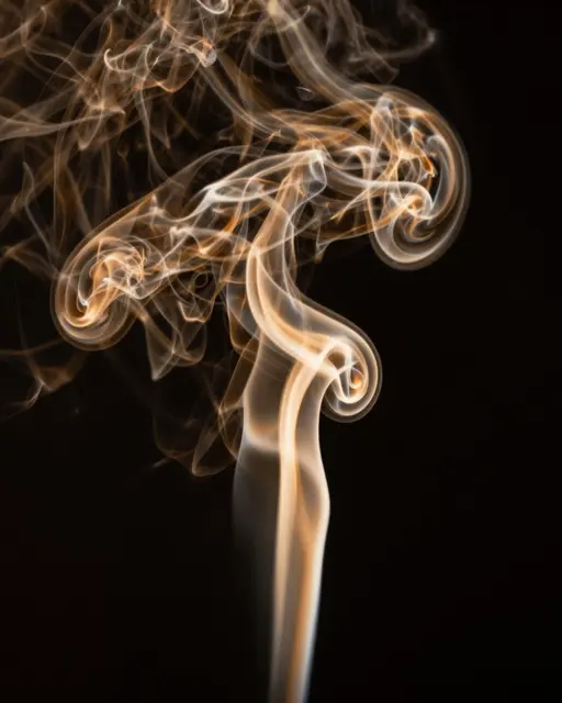 Warm glowing amber smoke curls twist and swirl against a solid black background