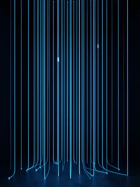 Vertical glowing blue light threads hang like a curtain in a dark room, with a few brighter threads.