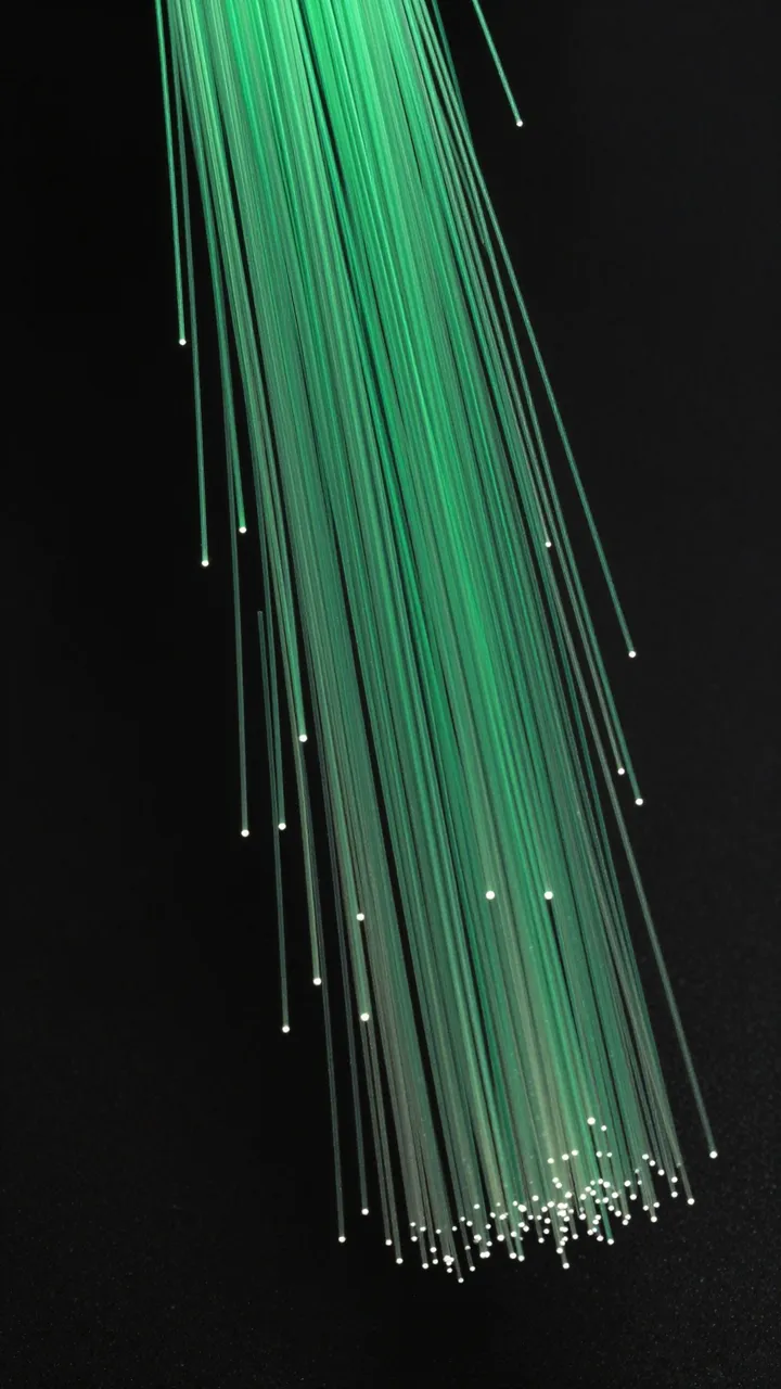 Vertical glowing emerald green fiber optic strands curve gently against a solid black background.