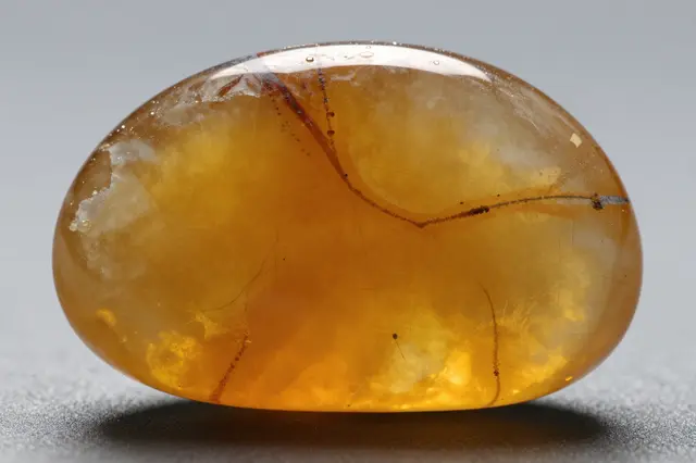 Close up of a smooth polished backlit honey onyx stone resting on a neutral gray surface