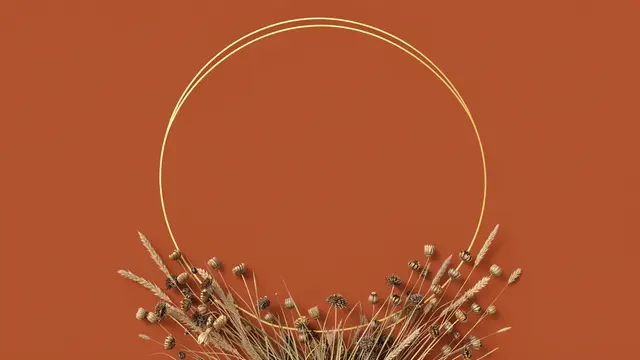 A thin double gold circle frame with dried grasses and seed heads on a rust orange background, empty inside the frame.