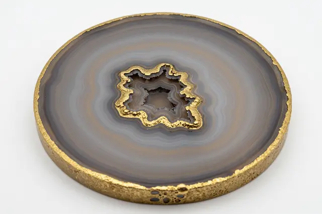 Round resin geode art with gold edges rests on a plain white background