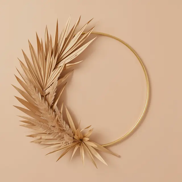 A thin gold hoop wreath adorned with dried palm leaves and pampas grass against a warm beige background