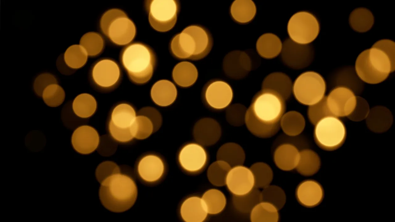 Soft out-of-focus warm golden bokeh circles of varying sizes scattered across a pure black background