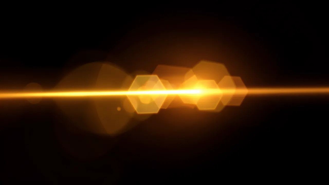 Horizontal warm golden lens flare with soft hexagonal bokeh ghosts on a solid black background