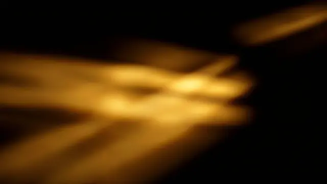 Soft streaky golden light leak bars glow across a solid pure black background